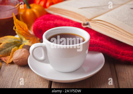 Accogliente e composizione con tazza di caffè, libro, foglie di autunno, zucca e coperta. Raccolto autunnale. Concetto di autunno. Foto Stock