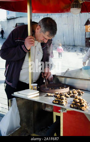 Istanbul, Turchia, Marzo 07, 2019: close up street venditore in piedi da strada tradizionale carrello distributore di castagno di vendita nella parte anteriore del Bazaar egiziano Foto Stock