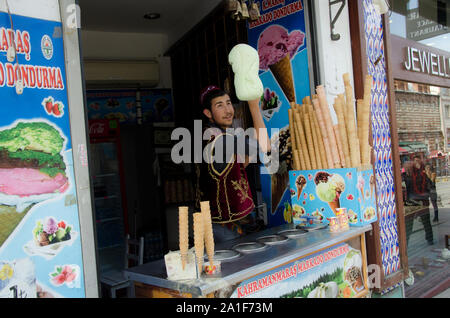 Istanbul, Turchia, marzo 07,2019: allegro giovane uomo in abbigliamento tradizionale manualmente facendo colorato deliziosi gelati sulla strada di Istanbul, Foto Stock