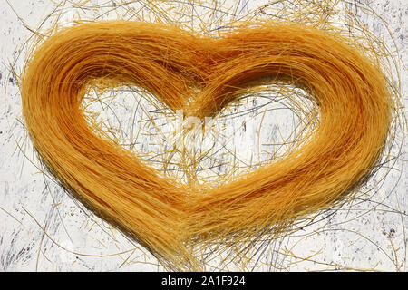 Non cotti i vermicelli di pasta a forma di cuore su uno sfondo di legno Foto Stock