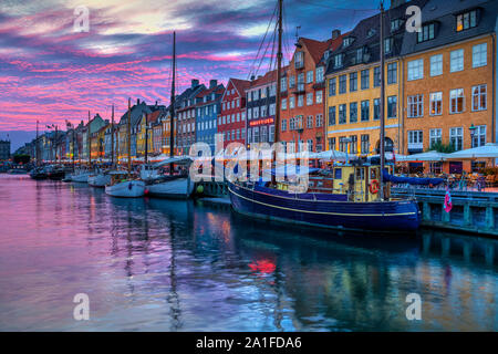 Una vista serale di colorate case a schiera lungo un canale nel quartiere di Nyhavn di Copenhagen, Danimarca. Foto Stock