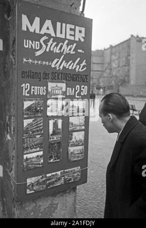 Touristen interessieren sich für ein impostare von 12 Fotos 'Mauer und Stacheldraht" di Berlino, Deutschland 1962. I turisti interessati a un set fotografico intitolato "Parete e filo spinato" presso un negozio di souvenir a Berlino, Germania 1962. Foto Stock