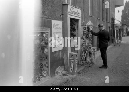 Turismo una einem Souvenir- und Andenkenladen a Berlino, Deutschland 1962. Tourist presso un negozio di souvenir a Berlino, Germania 1962. Foto Stock