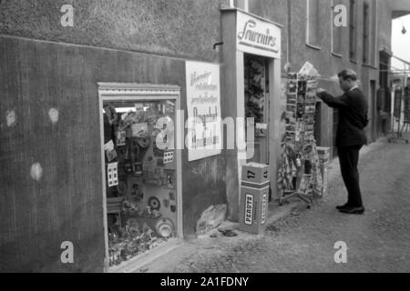 Turismo una einem Souvenir- und Andenkenladen a Berlino, Deutschland 1962. Tourist presso un negozio di souvenir a Berlino, Germania 1962. Foto Stock