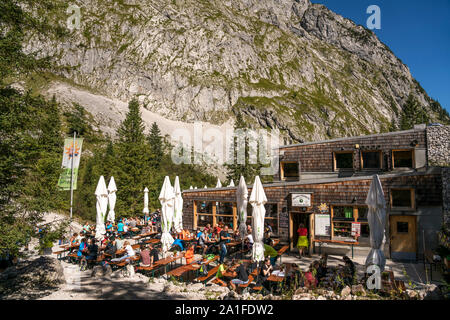 Wanderer auf der Terrasse der Berghütte Höllentalangerhütte im Höllental bei Grainau, Garmisch-Partenkirchen, Oberbayern, Bayern, Deutschland | escursione Foto Stock