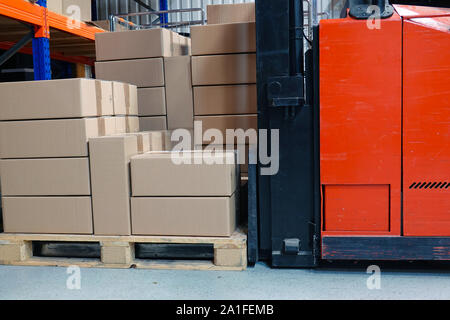 Scatole di cartone e il carrello elevatore in magazzino. Chiudere fino in vista laterale. Foto Stock