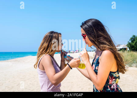 L'amicizia e il concetto di tempo libero - gruppo di felice giovani donne o amici di sesso femminile la tostatura di bevande analcoliche in estate spiaggia Foto Stock