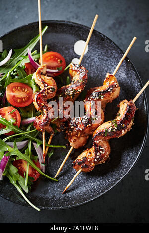 Satay spiedini di pollo con pomodorini e cipolla rossa fresca e rucola. Foto Stock