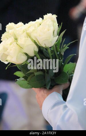 Close up di una mano di un uomo con un mazzo di rose bianche. Le rose per il mio amore per te. Foto Stock