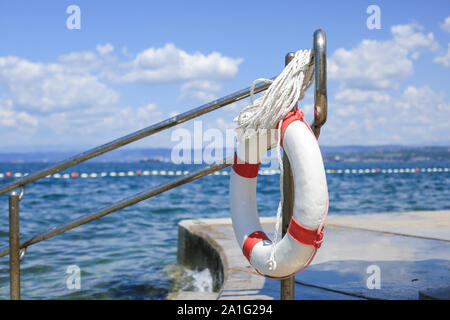 Ciambella di emergenza appeso alla recinzione vicino al mare in spiaggia Foto Stock