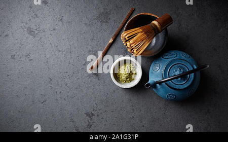 Una disposizione di una ghisa teiera, matcha in polvere e mescolare con una frusta di tè; laici piana; spazio copia; cultura asiatica Foto Stock