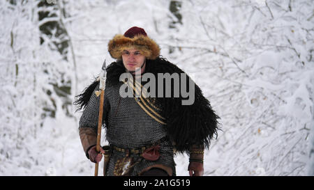 L'uomo viking andando nella foresta d'inverno. Ha vestito in abiti medievali. Foto Stock