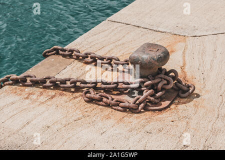 Rusty catena sul posto barca bollard sul dock closeup - nave ancorata sul porto Foto Stock