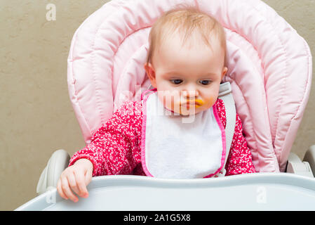 Chiudere la vista del volto della bambina nella PRAM con bocca sporca mentre viene alimentato Foto Stock