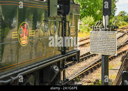 Cranmore, INGHILTERRA - LUGLIO 2019: Motore a vapore in attesa a Cranmore sulla East Somerset Railway. Sulla destra c'è un cartello originale della Great Western Railway Foto Stock