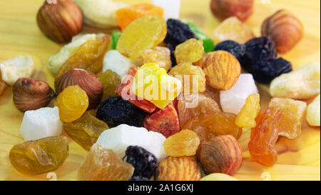 Tutti frutti. Mix di frutta secca (uva passa, cedro, mango) e dadi (mandorle, nocciole) sulla luce di legno superficie lucidata Foto Stock
