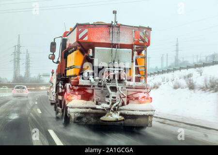 Arancio brillante gritter manutenzione carrello sbrinamento spargimento sale e sabbia sulla autostrada, Vista dalla guida auto dietro Foto Stock