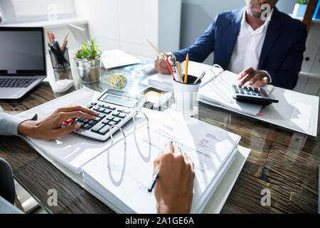 Due colleghi di lavoro Calcolo delle imposte in Office Foto Stock