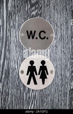 Segno per wc unisex su una porta grigia Foto Stock