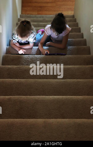 Due bambini che giocano sui loro dispositivi elettronici Foto Stock