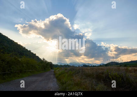 Tramonto con nuvole e sunray nel sentiero attorno El Croscat vulcano in Garrotxa Zona Vulcanica parco naturale (Santa Pau, La Garrocha, Girona, Spagna) Foto Stock