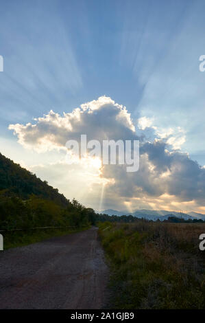 Tramonto con nuvole e sunray nel sentiero attorno El Croscat vulcano in Garrotxa Zona Vulcanica parco naturale (Santa Pau, La Garrocha, Girona, Spagna) Foto Stock