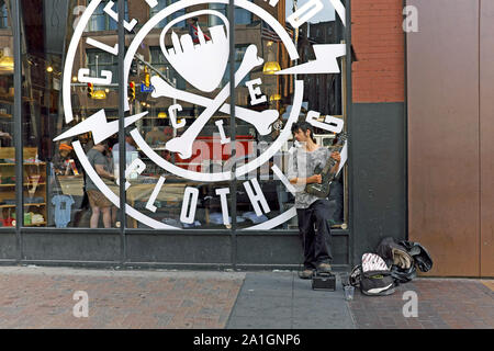 Suonatore ambulante di strada suona la chitarra elettrica sul marciapiede fuori del Cleveland Clothing Company su Euclid Avenue nel centro di Cleveland, Ohio, USA. Foto Stock