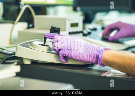 Le mani di uno scienziato su un pannello di ontrollo di un microscopio elettronico. Foto Stock