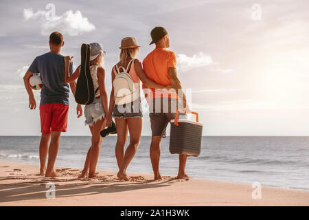 Quattro amici di riposo al tramonto picknic sulla spiaggia del mare Foto Stock