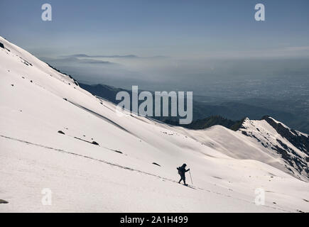 Turista nella neve nel percorso di belle montagne in inverno con vista città Foto Stock