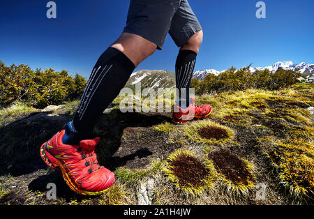 Close up di un escursionista gambe in rosso sono scarpe da arrampicata in montagna in cielo blu sullo sfondo. Uno stile di vita sano. Esterno il concetto di viaggio. Foto Stock