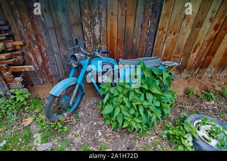 Un vecchio abbandonato cavalletto di motoveicoli nei pressi di una recinzione Foto Stock