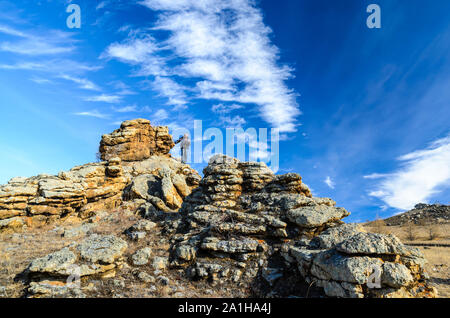 Regione di Irkutsk, Russia, Sakhurta - 19 ottobre 2013: L'uomo rimane sulla roccia nella steppa di Tazhenranskaya sulla costa occidentale del lago Baikal, Siberia Foto Stock