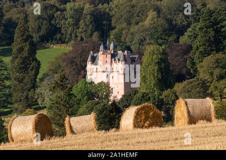 Una vista sui terreni del Castello di Craigievar immerso nel bosco con le balle di paglia in primo piano Foto Stock