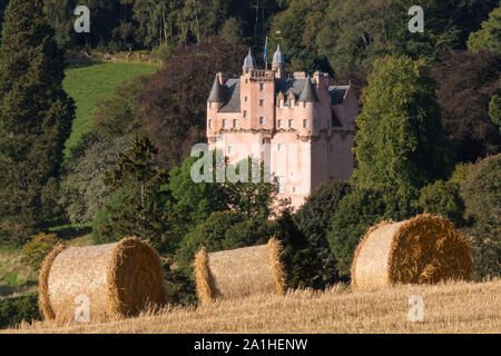 Una vista sui terreni del Castello di Craigievar immerso nel bosco con le balle di paglia in primo piano Foto Stock