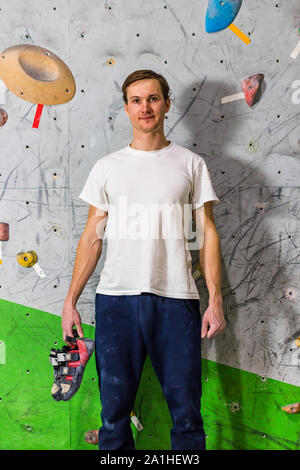 Ritratto di rocciatore uomo appeso rocky calzatura in una bouldering parete di arrampicata. Foto Stock