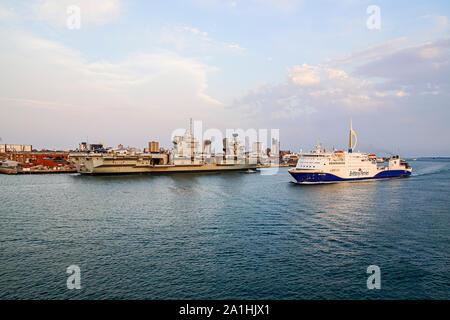 Brittany Ferries car e passeggero traghetto RoPax Baie de Seine arrivando a Portsmouth Hampshire REGNO UNITO Inghilterra con portaerei Queen Elisabeth ormeggiati Foto Stock