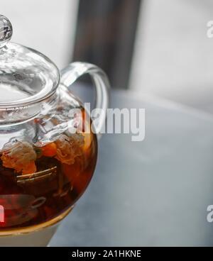 Tè nero con goji (chinese wolfberries) e gelsomino nella teiera di vetro sulla tavola nera Foto Stock