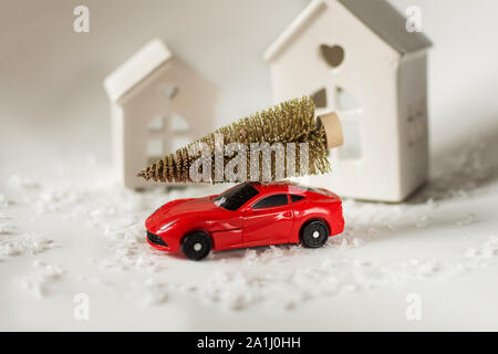 Vacanze di Natale concetto con un luminoso albero di natale sul rosso auto giocattolo e neve intorno ad esso. Foto Stock