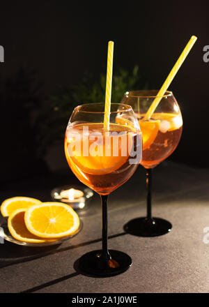 Due bicchieri di italiano aperol spritz cocktail con fettine di arancio su sfondo nero. Foto Stock