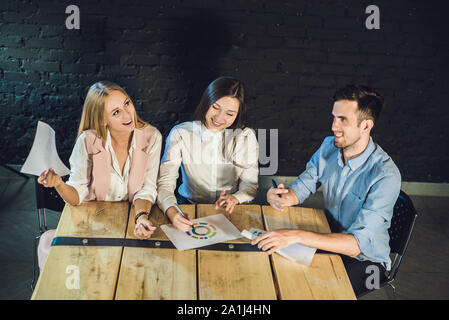 Team di giovani collaboratori rendendo grande incontro di discussione nel moderno ufficio coworking. Processo del lavoro di squadra. Posizione orizzontale,sfondo sfocato. Foto Stock