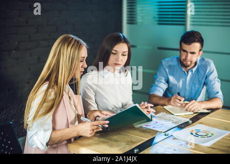 Team di giovani collaboratori guardando storyboard per le riprese video in moderno ufficio coworking. Processo del lavoro di squadra. Posizione orizzontale,sfondo sfocato. Foto Stock