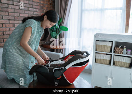 Madre della preparazione mette la bambina in un seggiolino per bambini Foto Stock