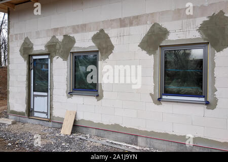 Facciata di edificio realizzato da blocchi di colore bianco con grandi finestre sotto lavori di costruzione. Foto Stock