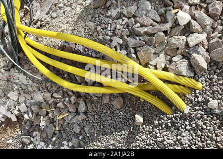 Il giallo di tubi per cavi elettrici o incollaggio di acqua dal suolo al sito in costruzione. Foto Stock