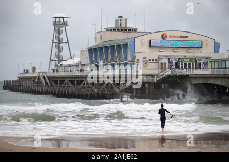 Un surfista prende il mare al largo Bournmouth beach nel Dorset. Foto Stock