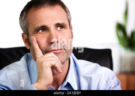 Fiducioso persona d'affari in appoggio il mento sulla mano e guardando verso l'alto. Foto Stock