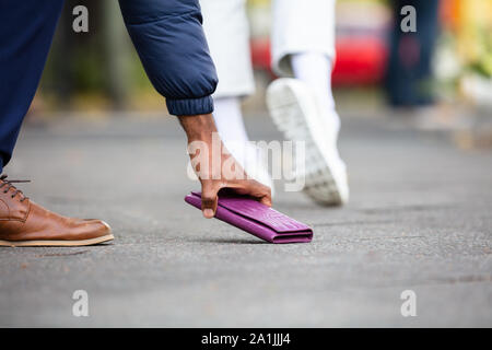 Persona di prelevare perso in borsa sulla strada Foto Stock