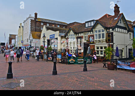 La gente seduta al di fuori del pub lungo il porto di Poole, compreso il Jolly Sailor e il Lord Nelson. Altri passeggiando lungo la strada. Foto Stock