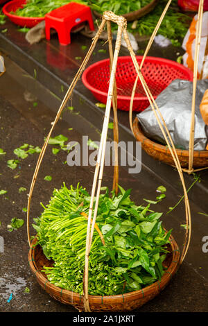 Produrre per la vendita in un tradizionale cestello pensili, Hoi An Street Market, Vietnam Foto Stock